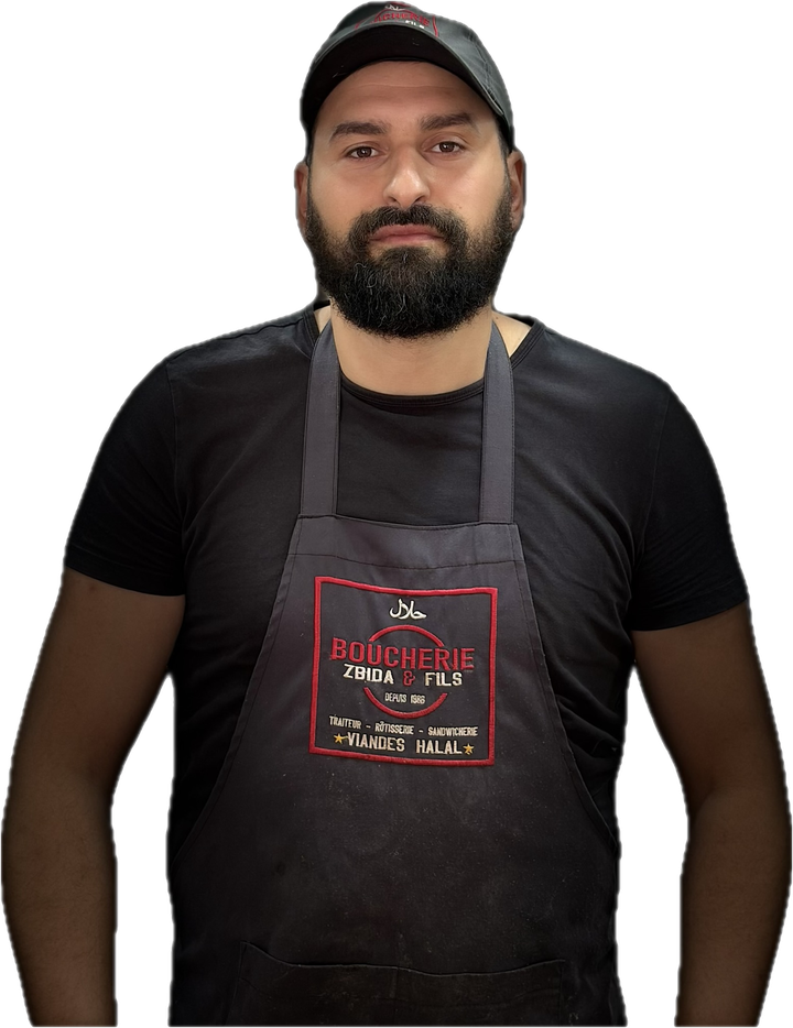 Younes Zbida, en tablier brodé Boucherie Zbida & Fils, devant son comptoir